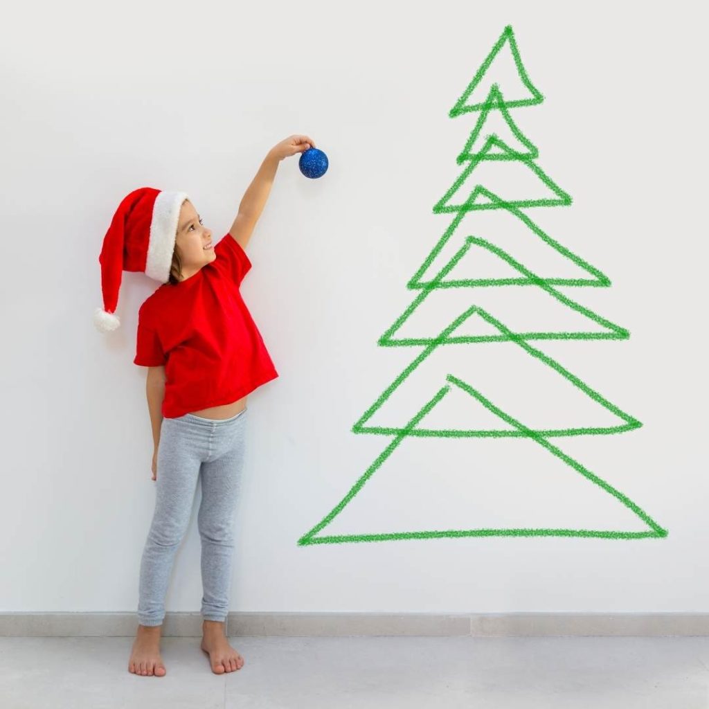 child drawing a christmas tree on wall