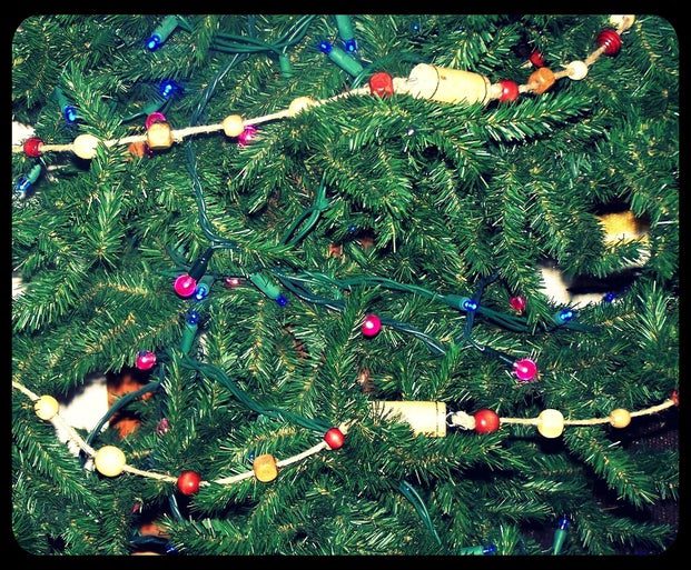 Close up of a Christmas tree with a wine cork garland wrapped around it.