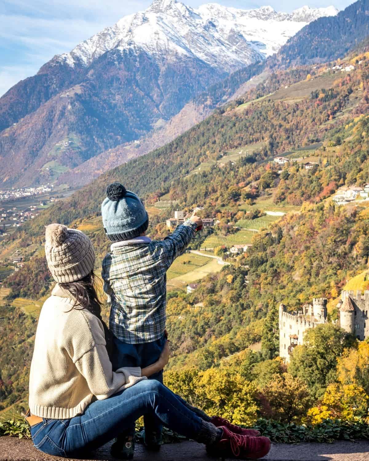 Woman holding a child while overlooking an autumn mountain valley in South Tyrol, illustrating a meaningful family experience gift.
