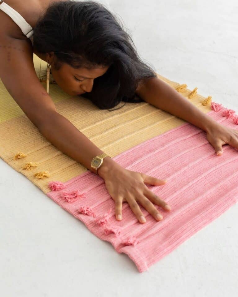 Woman stretching on an Oko Living GOTS-certified organic cotton yoga rug colored with plant-based herbal dyes.