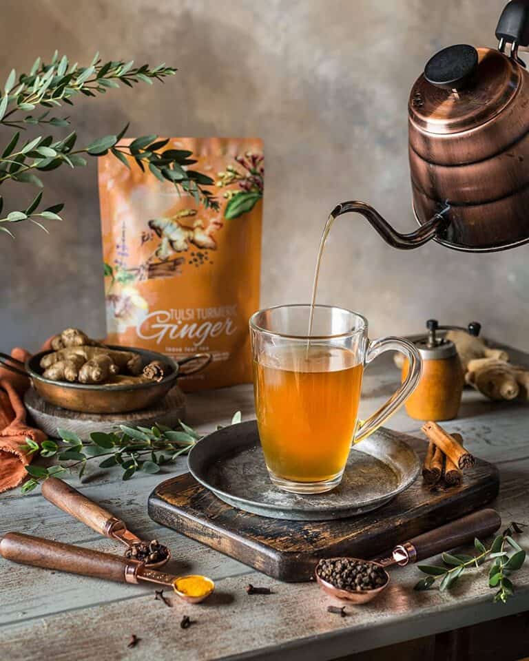 A blooming flower tea unfurls in a clear glass teapot, surrounded by Teabloom’s elegant packaging—highlighting their organic, handcrafted tea experience.