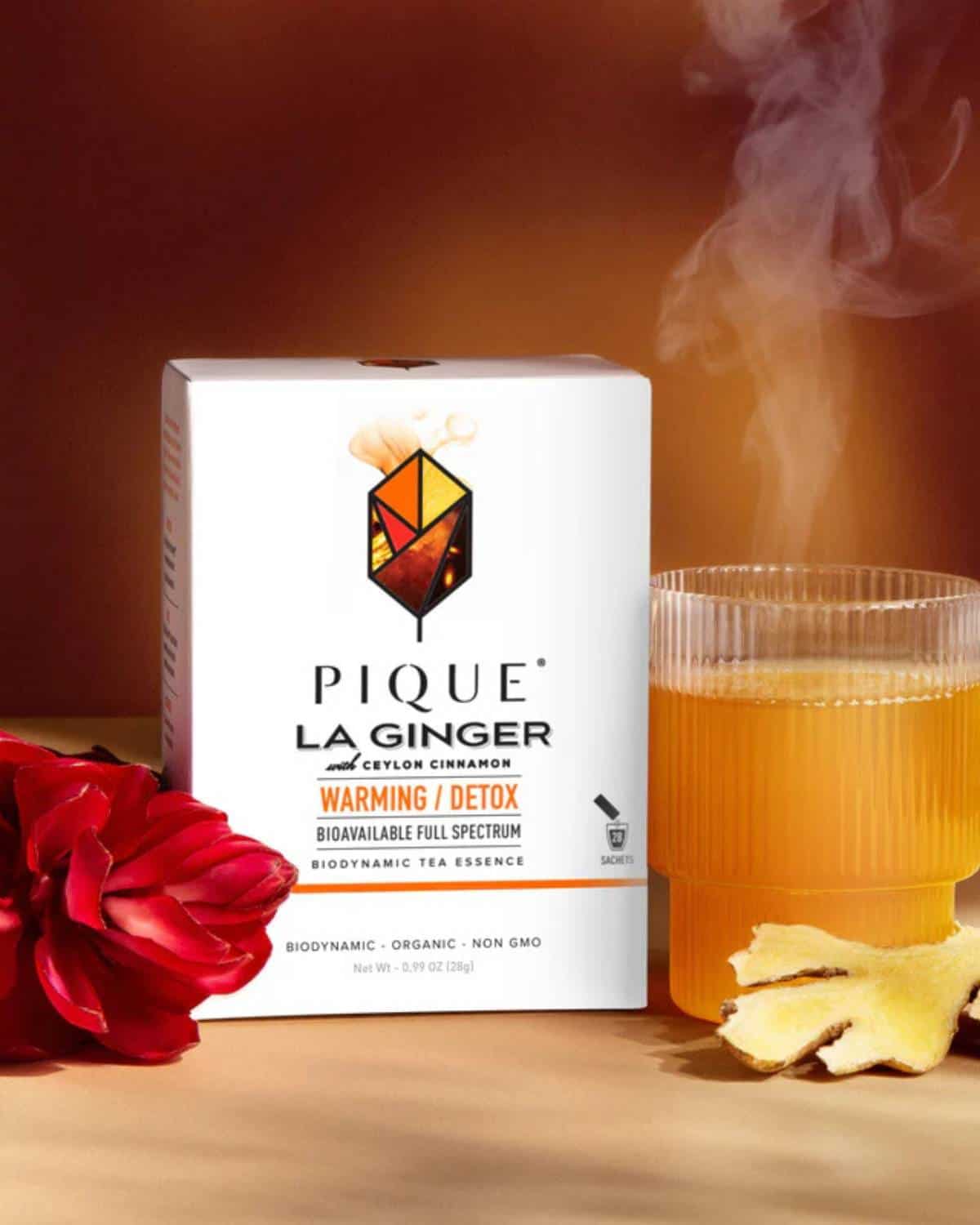 Glass mug filled with amber-colored tea beside Pique Tea crystals and minimalist packaging, showcasing a clean and modern organic tea option.