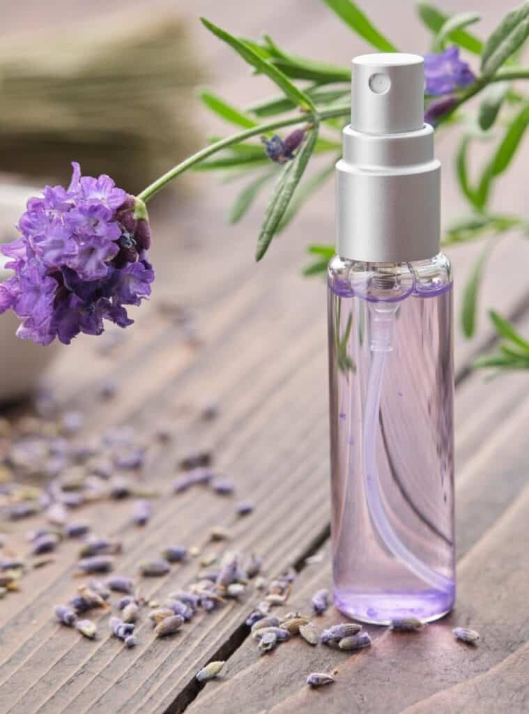 Glass spray bottles with natural homemade body mist, labeled with handwritten tags and floral scents.