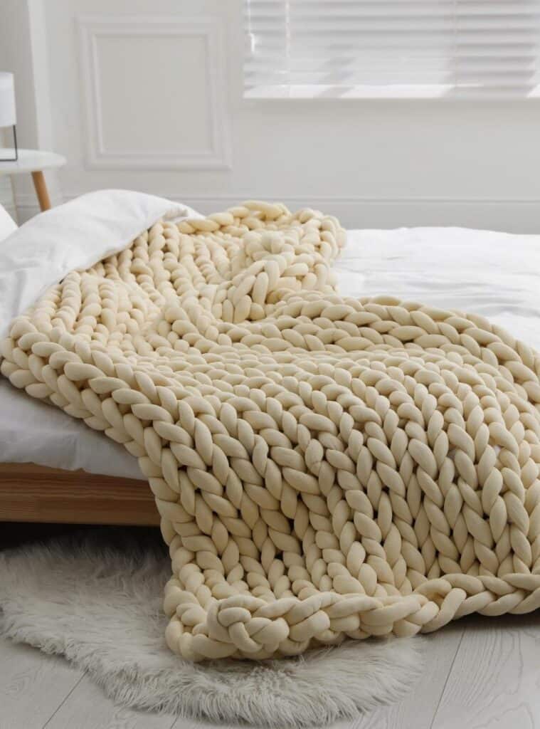 Chunky hand-knit blanket folded neatly with a ribbon, gifted as a homemade cozy Christmas present.