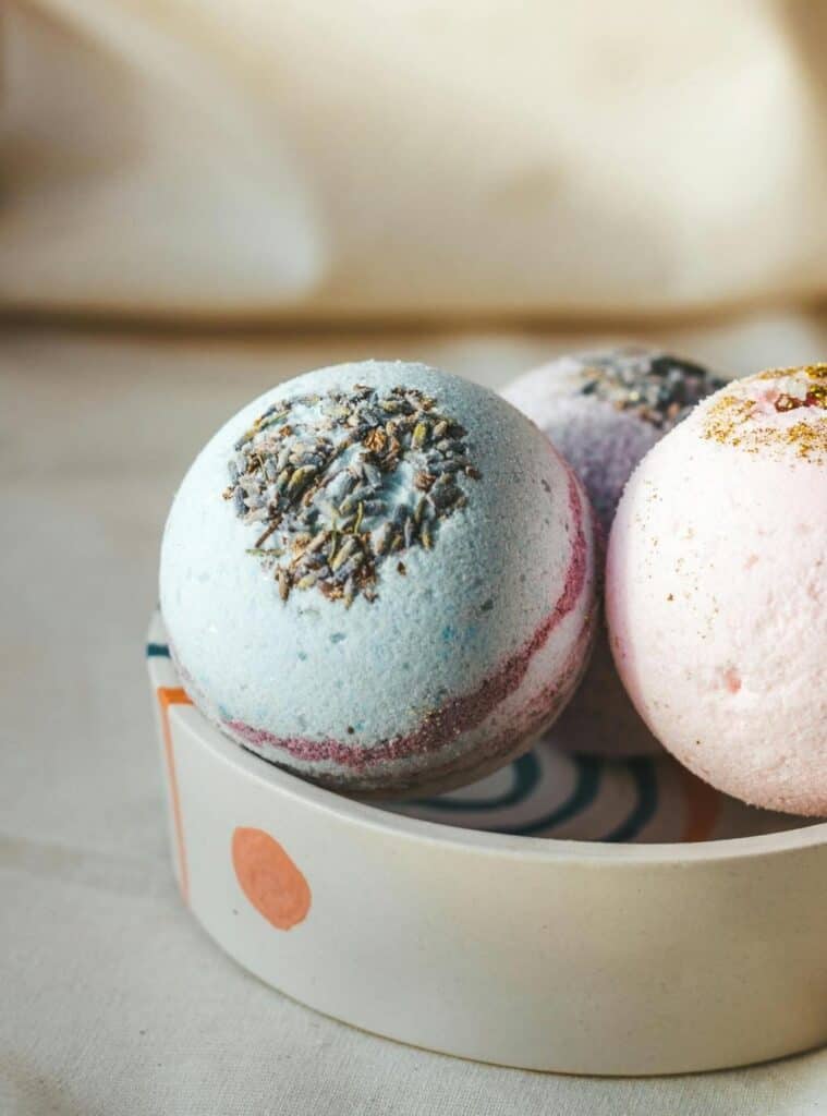 Colorful handmade bath bombs in a wooden tray, wrapped for gifting as a natural DIY Christmas gift.