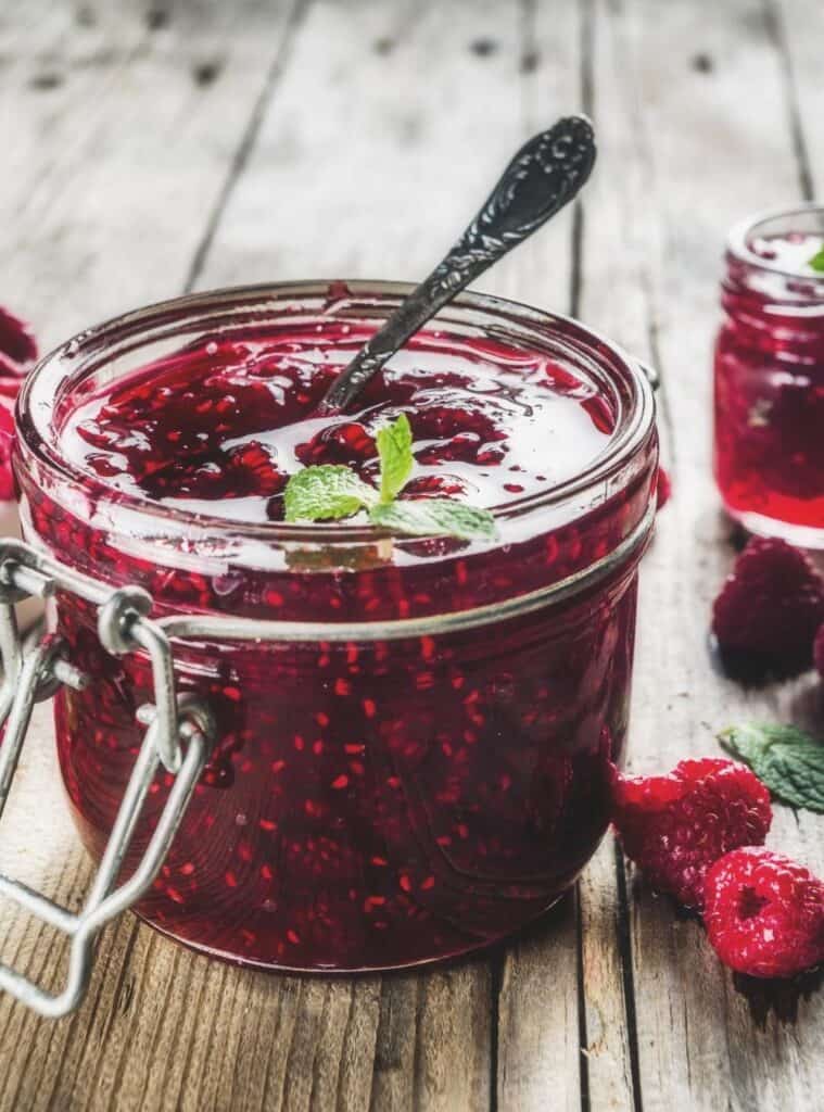Jar of homemade jam with a handwritten tag and twine, set on a rustic holiday table as a DIY Christmas gift.