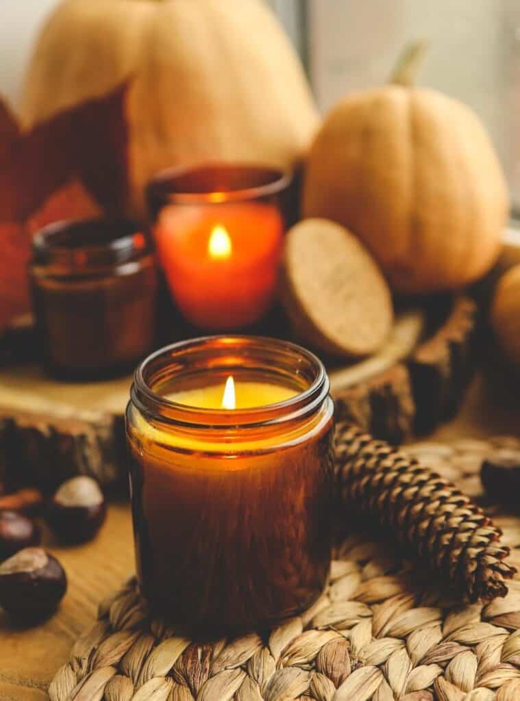 Hand-poured soy candles in glass jars with dried flowers and essential oils, ready as homemade Christmas gifts.