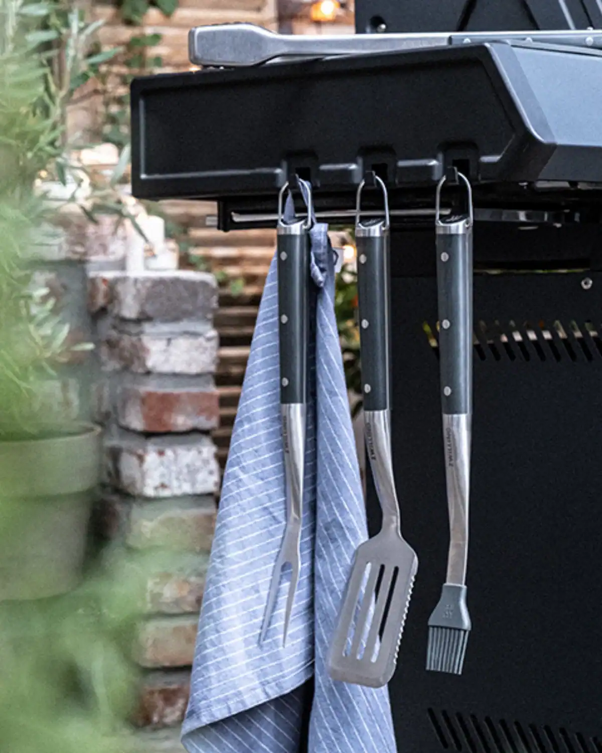 Zwilling stainless steel grill tool set stored in a reusable canvas wrap, a long-lasting eco-upgrade for grill-loving dads.