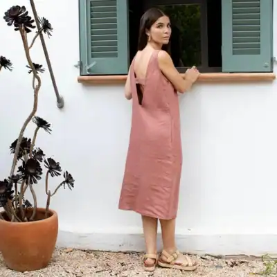 MagicLinen blush pink linen pinafore dress featuring a relaxed midi silhouette, open back detail, and breathable European linen fabric.