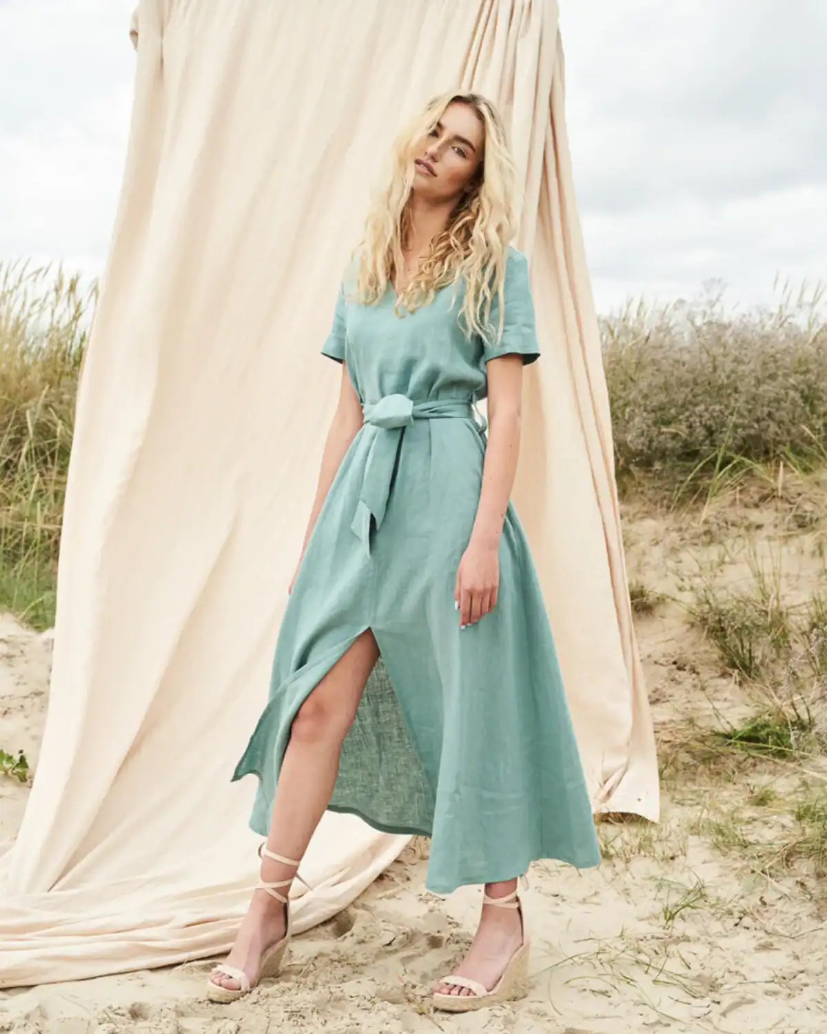 Woman wearing the Linen Handmade Studio Vivien linen maxi dress with a V-neckline, short sleeves, waist belt, and front slit.