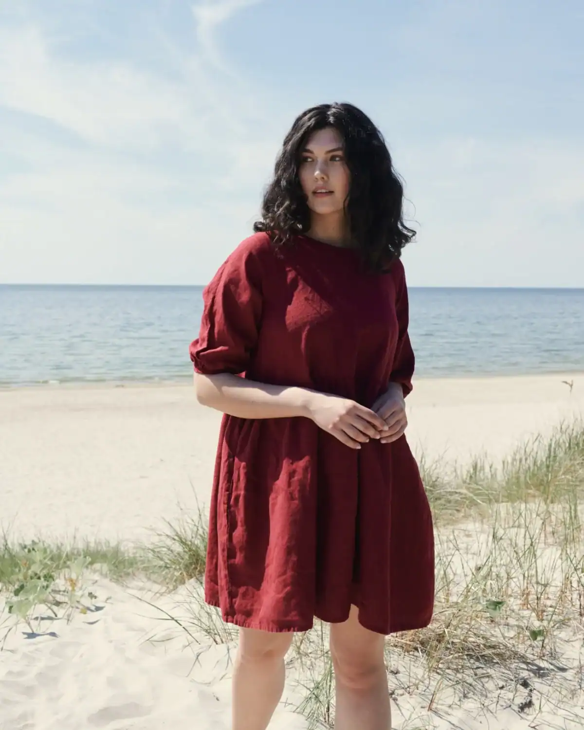 Woman wearing the Linenfox Beth linen dress in burgundy red with an oversized A-line shape, raglan sleeves, and gathered cuffs.