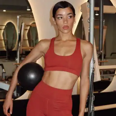 Woman wearing a MATE Organic Sports Bra and leggings made with GOTS-certified organic cotton in a gym.