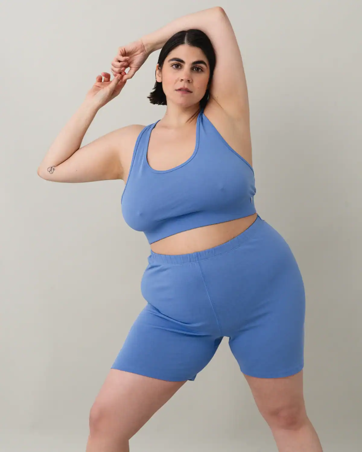 Woman stretching in ODDOBODY bike shorts and shelf bra made from 100% GOTS-certified organic Pima cotton.