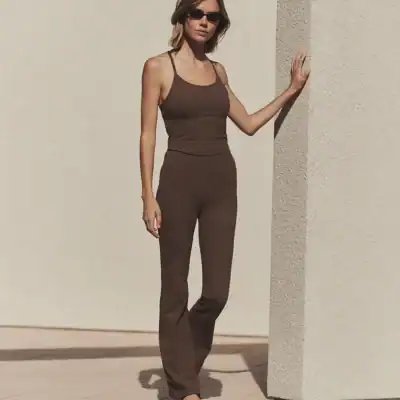 Woman wearing brown Pact Organic Bootcut Leggings, a lower-synthetic organic cotton option for everyday wear.