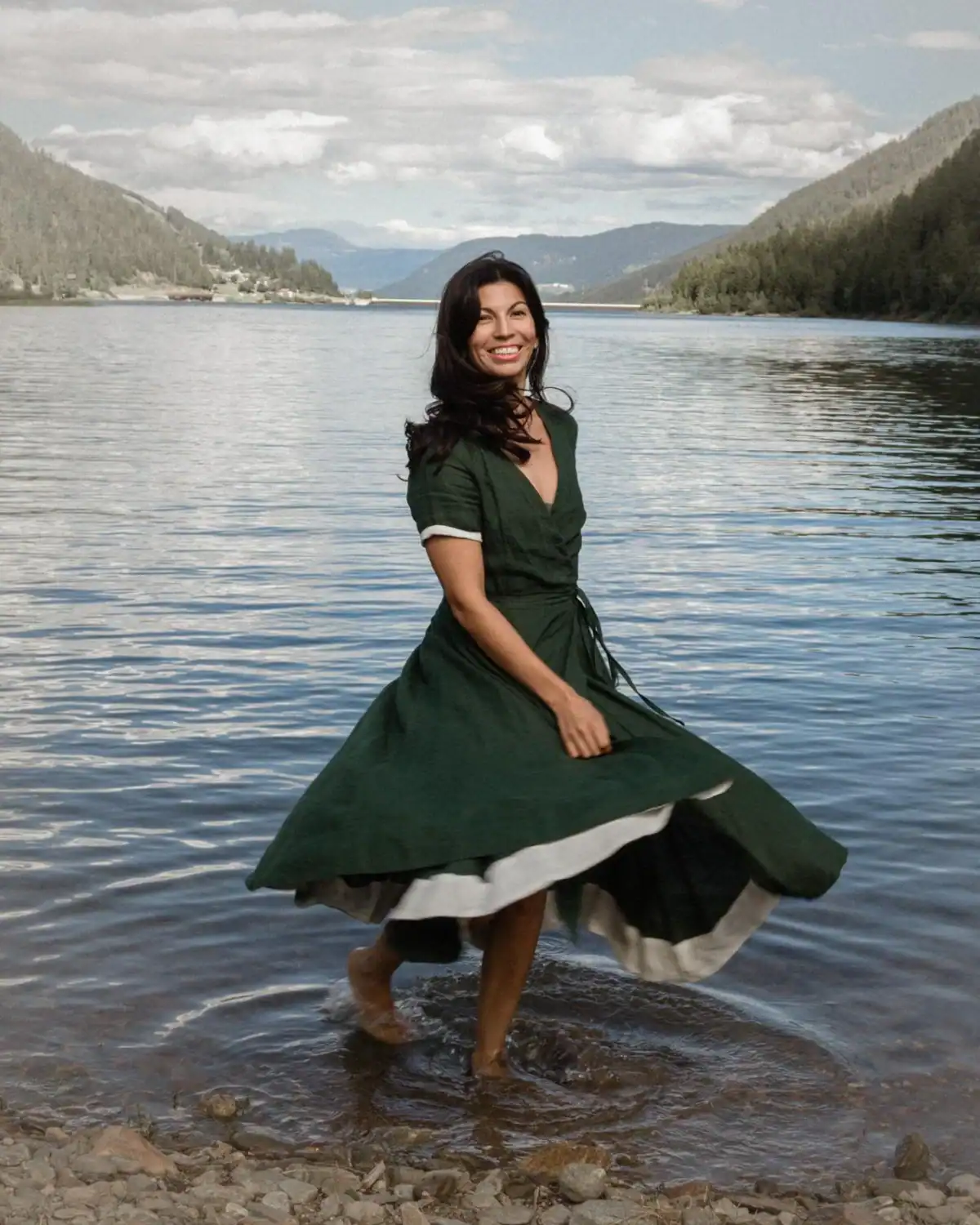 Woman wearing the Son de Flor Evergreen linen wrap dress with short sleeves, a defined waist, contrasting white trim, and a full skirt.