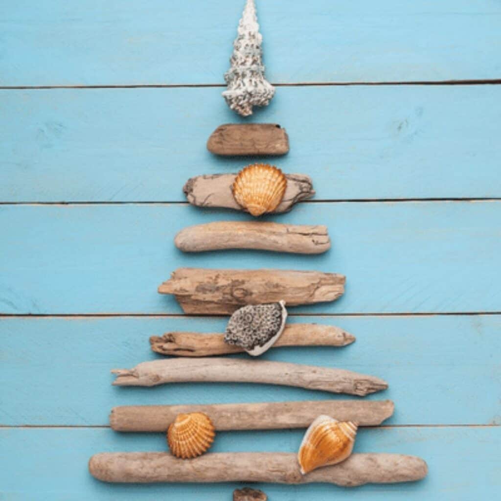 Rustic Christmas tree crafted from stacked driftwood branches and topped with a wooden star for an eco-friendly holiday display.