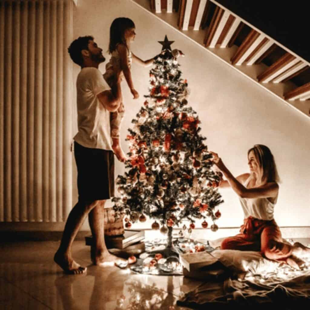 Family decorating a traditional Christmas tree together with lights and ornaments during the holiday season.