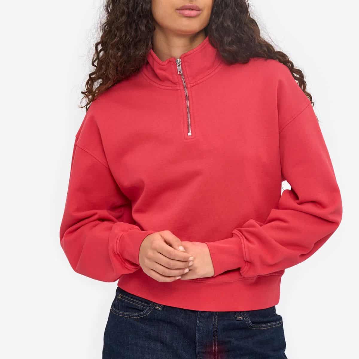 Woman wearing a red quarter-zip sweatshirt featured as a bonus pick in a guide to non-toxic sweaters and cardigans