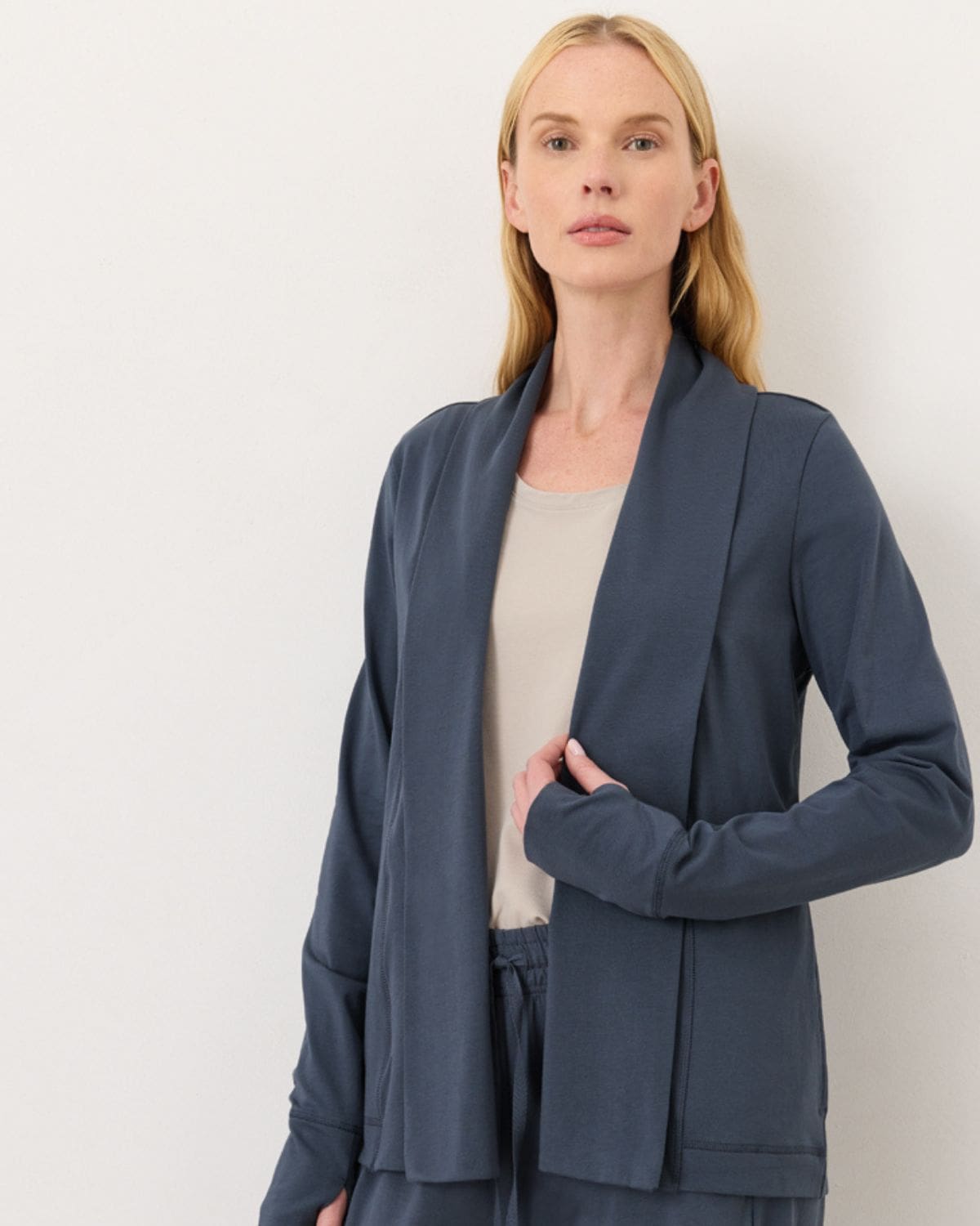 Woman wearing a slate blue Pact organic cotton open-front cardigan over a neutral tank and matching pants