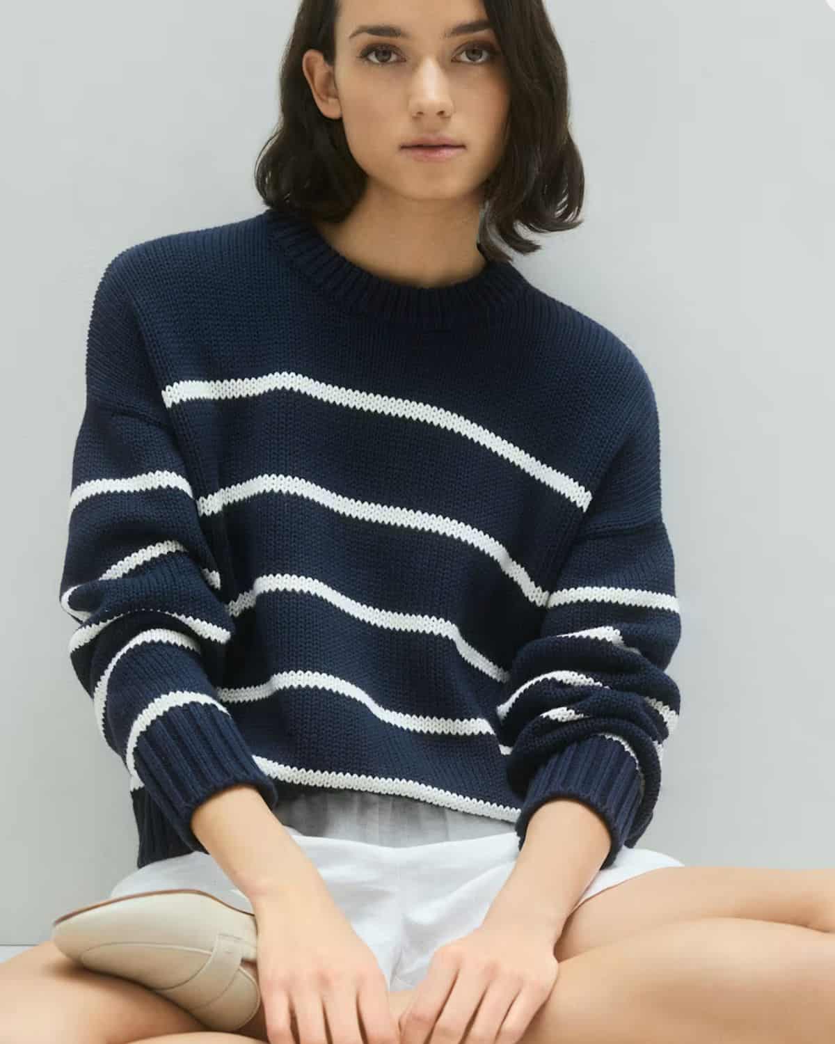 Woman wearing a navy and white striped Quince 100% organic cotton crewneck sweater with white shorts