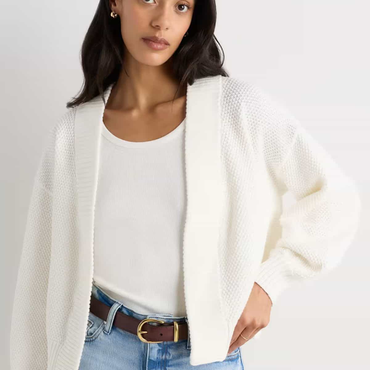 Woman wearing a white Quince 100% organic cotton open-front cardigan over a white tank and jeans