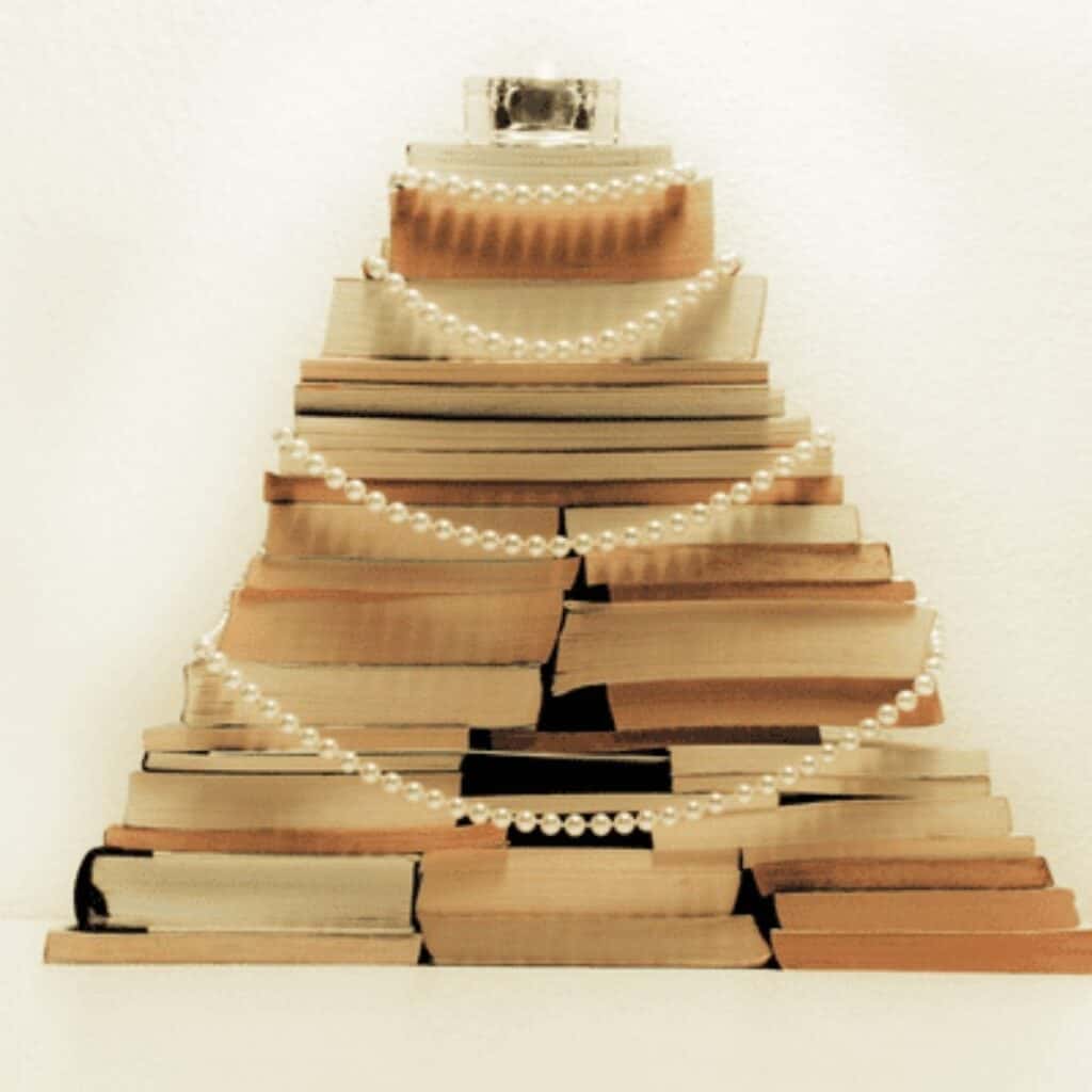 DIY Christmas tree made by stacking books into a tree shape and decorating with pearl garland.