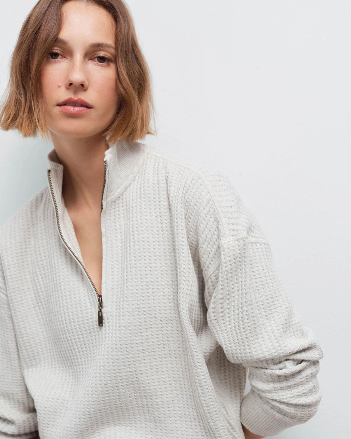 Woman wearing a light gray organic cotton waffle half-zip sweater featured in my tested guide to the best non-toxic sweaters and cardigans.