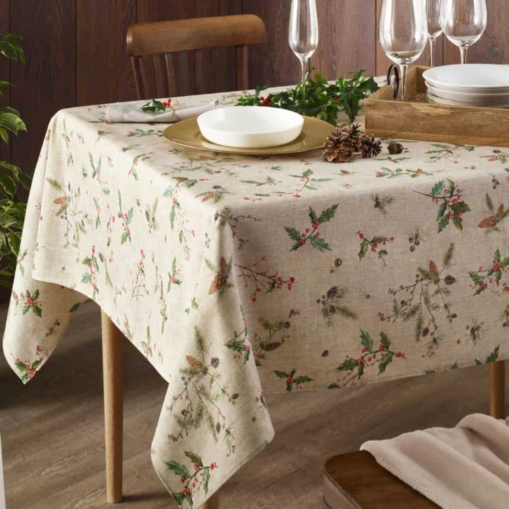 Non-toxic Christmas table decor with evergreen branches, pinecones, reusable dishes, and cloth linens.