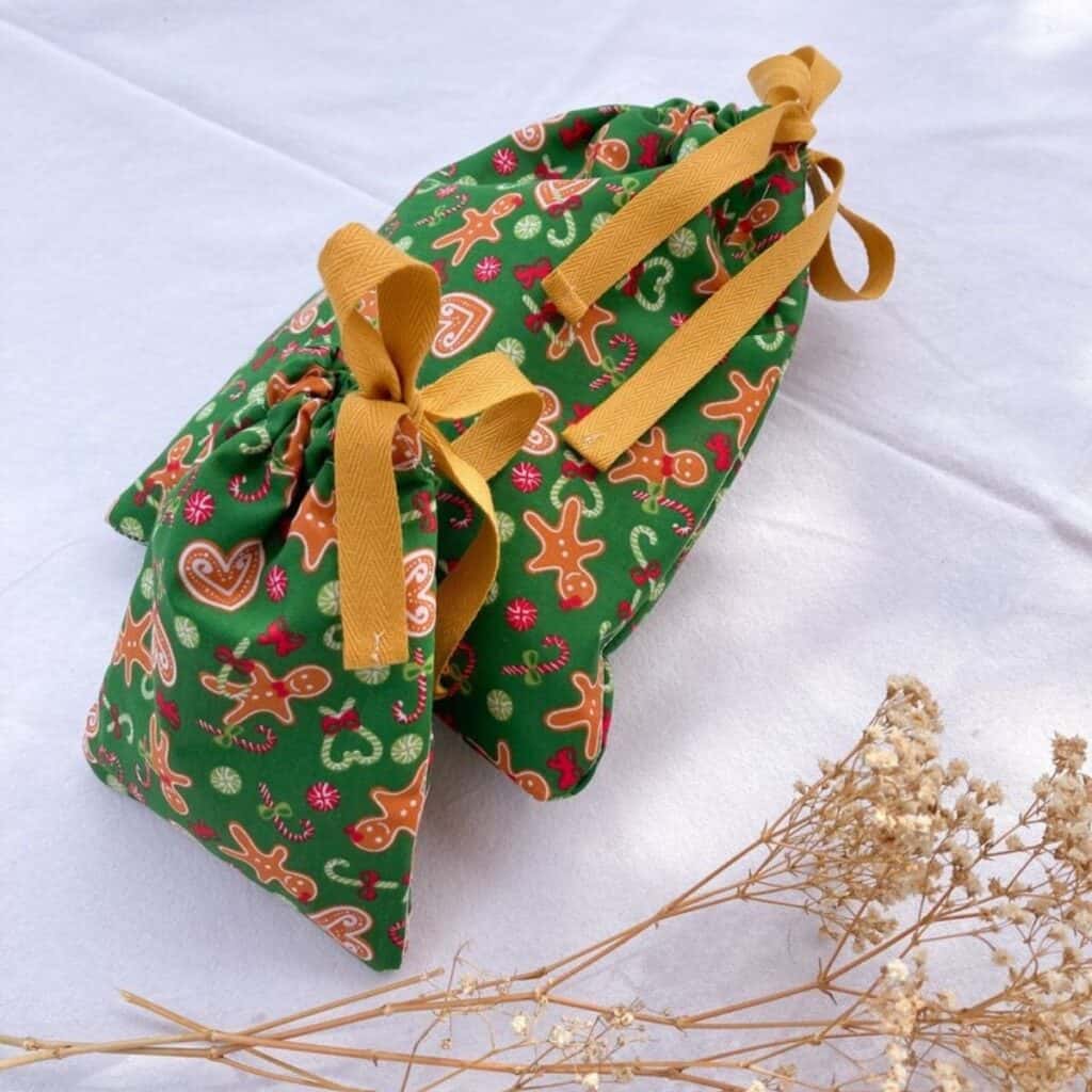 Reusable fabric Christmas gift bag with holiday print and ribbon handles for eco-friendly non-toxic Christmas gift wrapping.