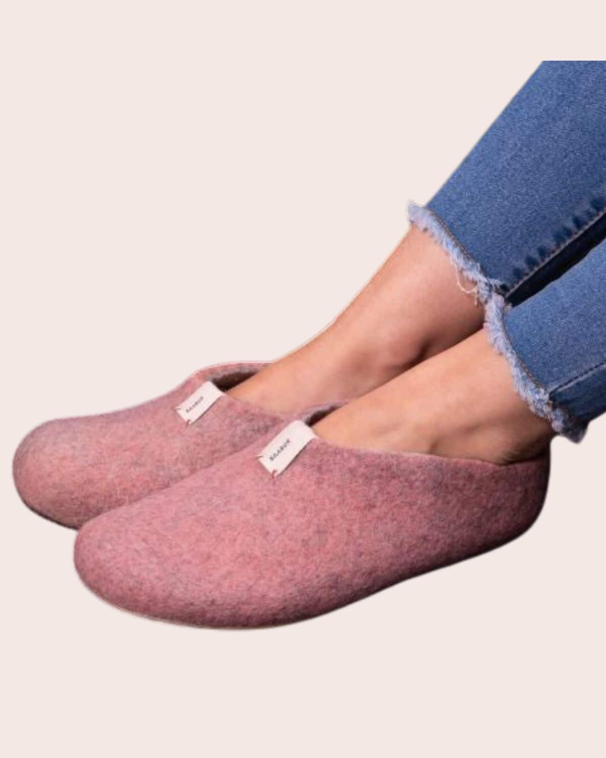 Pink Baabuk Mel felted wool slippers with closed toes and open backs, worn with cropped blue jeans.
