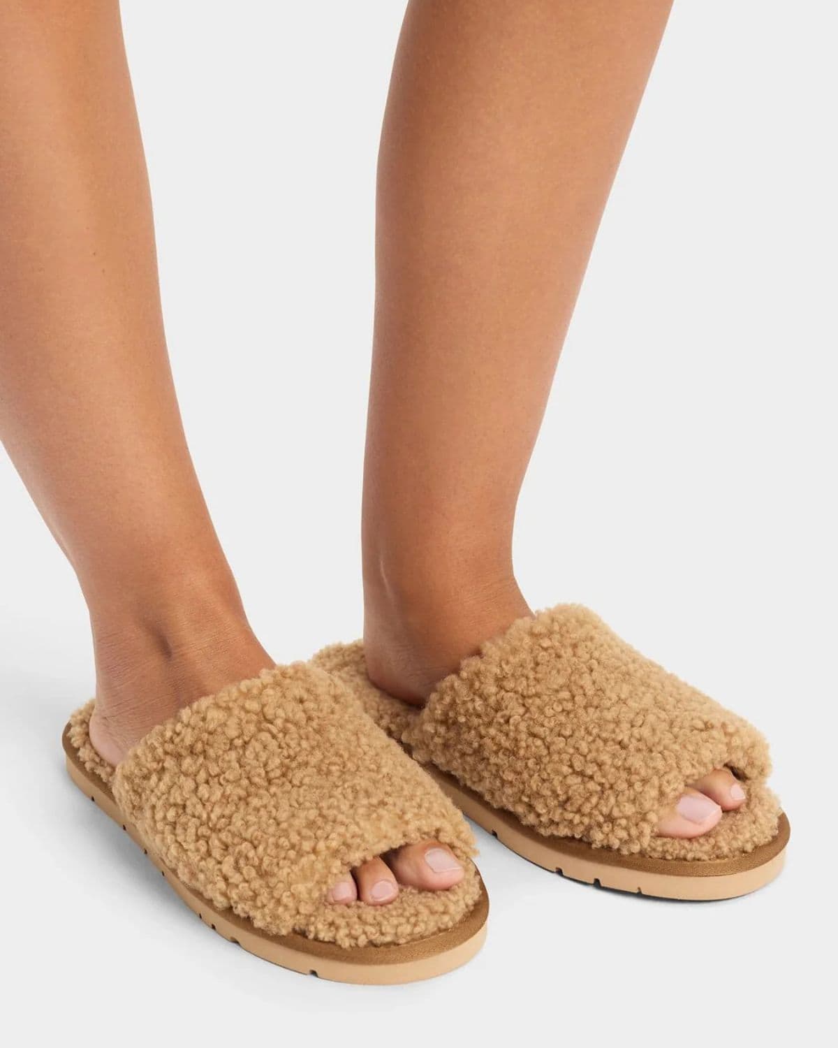 Tan Cozy Earth Puffy Sheep Slides worn on bare feet, with fluffy wide straps, open toes, and thick beige soles.